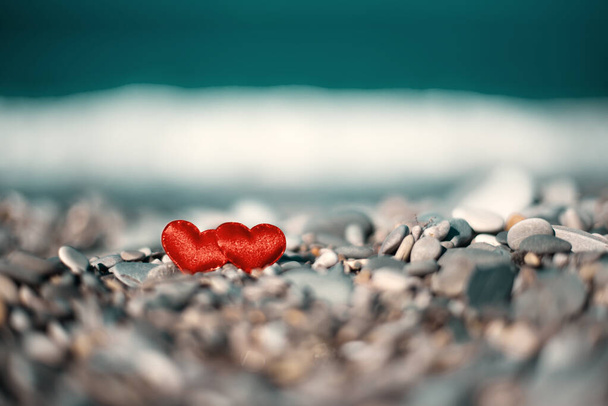 two red hearts on stones on a blurred background on the seashore. Love symbol - Photo, Image
