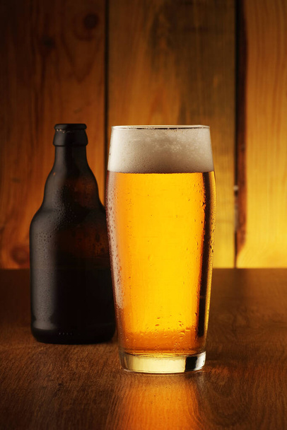 Krug mit Bier und Flasche auf Brettern und Holzhintergrund - Foto, Bild