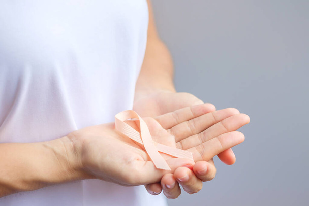 woman hand holding Peach Ribbon for September Uterine Cancer Awareness month. Healthcare and World cancer day concept - Fotoğraf, Görsel