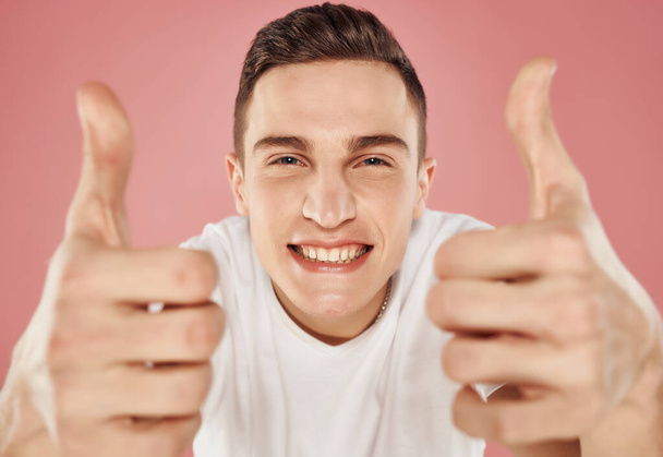 χαριτωμένος τύπος σε λευκό t-shirt συναισθήματα close-up χειρονομία με τα χέρια ροζ φόντο - Φωτογραφία, εικόνα