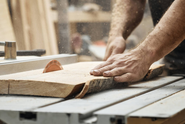 Closeup of a carpenter's hand. Works on a board sawing machine in his workshop. - Foto, Bild