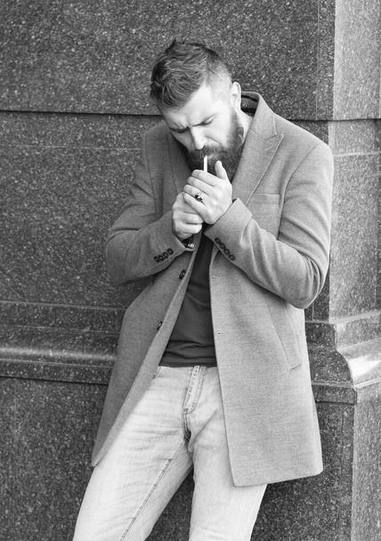 bearded hipster guy with stylish hairdo wear jacket and jeans having a little break for smoking cigarette, hipster lifestyle - Φωτογραφία, εικόνα