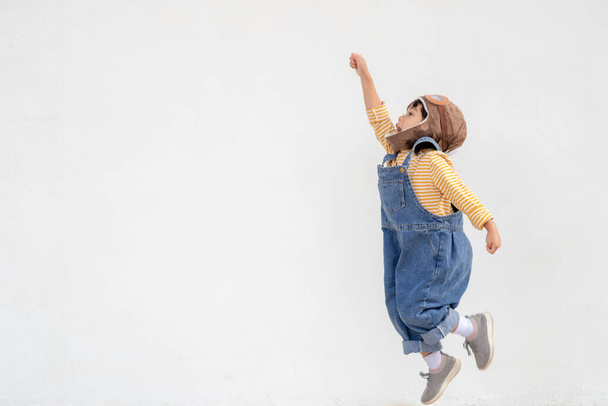 dromen van vliegen! klein kind meisje spelen met een pilot hoed op witte achtergrond - Foto, afbeelding