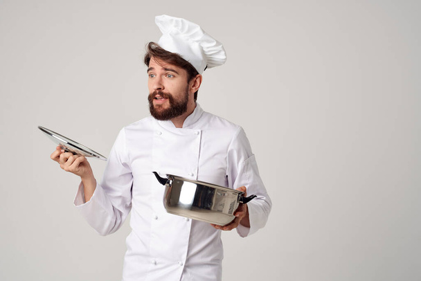 Chef masculino alegre mirando en la sartén preparando comida gourmet - Foto, Imagen