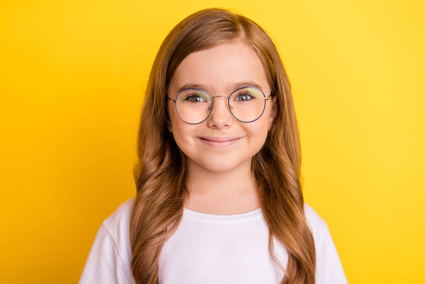 Photo of little cute blond girl wear spectacles white t-shirt isolated on yellow color background - Foto, immagini