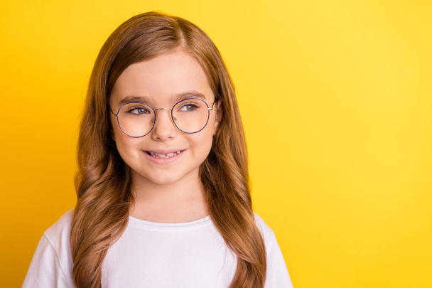 Photo of young little girl happy positive smile dream curious look empty space isolated over yellow color background - Φωτογραφία, εικόνα