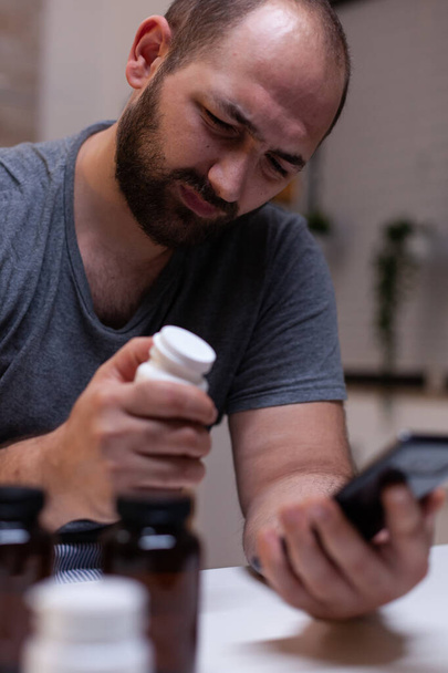 Uomo caucasico con mal di testa guardando smartphone - Foto, immagini
