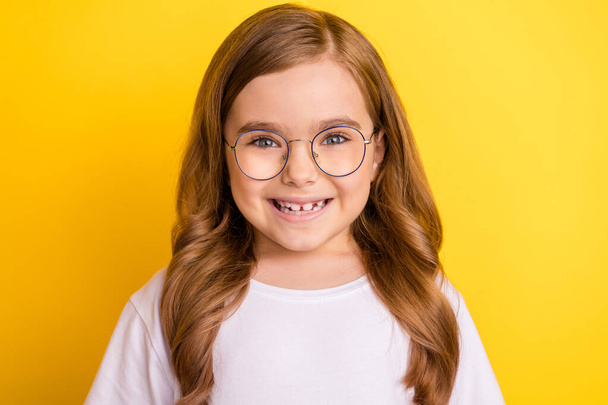 Photo of young little girl happy positive toothy smile wear glasses isolated over yellow color background - Photo, Image