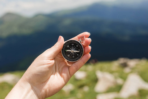 Woman holding a compass in hand on nature background, ready to travel, keep calm. Tourism, traveling, hiking and healthy lifestyle concept. - Photo, Image