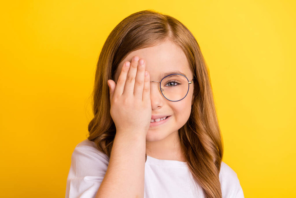 Küçük kızın fotoğrafı mutlu bir gülümseme, göz kapağı, göz kontrolü, görüş uzmanı sarı arkaplan üzerinde izole edilmiş. - Fotoğraf, Görsel