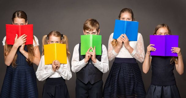 School Children Cover Face by Book. Kids Eyes Looking at Camera hiding by Rainbow Color Books. Group of Student Learning Reading. Diversity Concept - 写真・画像