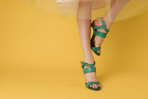 green shoes on female legs posing close-up yellow background - Фото, зображення