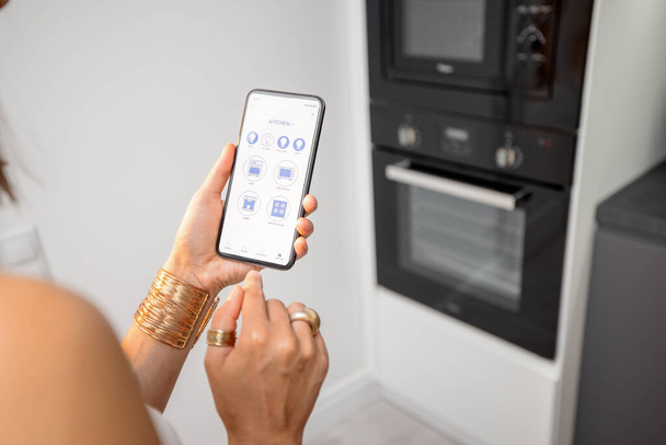 Controlling smart devices with phone on the kitchen - Photo, image
