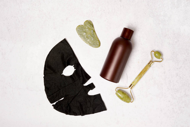 Набір самодопомоги. Ролик для обличчя, скребок для масажера Guasha, пляшка косметичної олії та маски для обличчя. Плоский прошарок
 - Фото, зображення