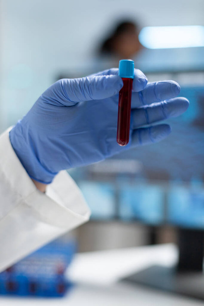Close-up van de bioloog onderzoeker die medische stofzuigers vasthoudt met bloedmonster - Foto, afbeelding