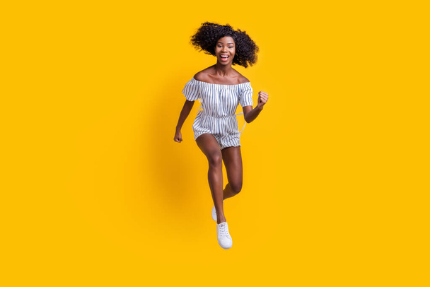 Full length body size view of attractive cheerful motivated slim fit girl jumping running fast isolated over bright yellow color background - Fotoğraf, Görsel