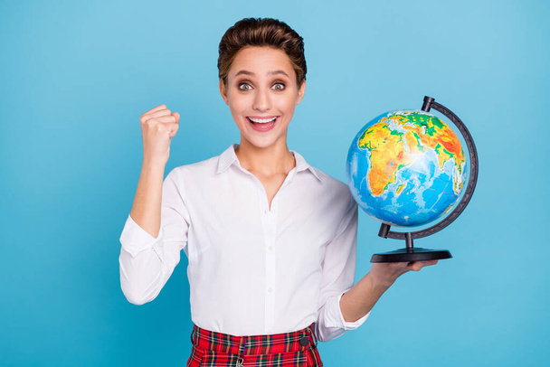 Photo of hooray blond millennial lady hand fist hold globe wear shirt isolated on blue color background - 写真・画像