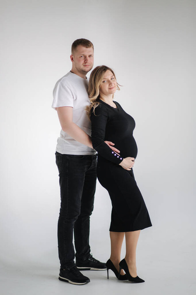 Happy future parents of man and pregnant woman puts hands on belly and waiting for beby movement in the belly - Fotografie, Obrázek