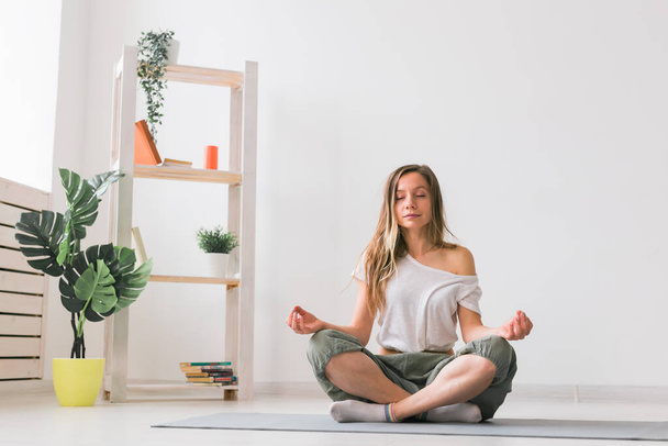 Młoda kobieta w pozycji lotosu podczas medytacji. Praktyka uważności, samopoczucie i samokoncepcja. - Zdjęcie, obraz