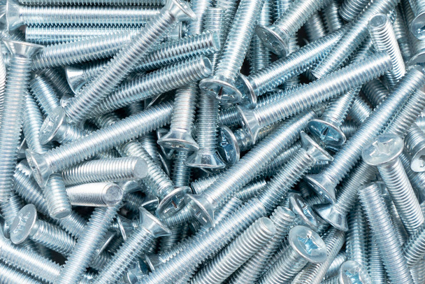 Metal bolts a row background. Chromed screw bolts texture. Steel bolts pattern. Set of bolts. Tools for work. - 写真・画像