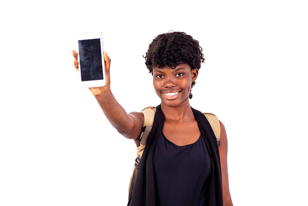 jovem estudante com mochila em pé sobre fundo branco apresentando telefone celular sorrindo - Foto, Imagem