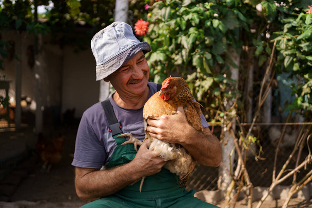 Smiling farmer holding a chicken - Foto, Bild