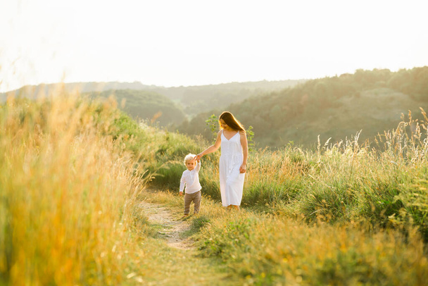 Madre e hijo están caminando en el campo verde - Foto, Imagen