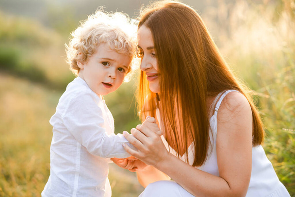Happy woman holding her son by the hand in nature - Photo, Image