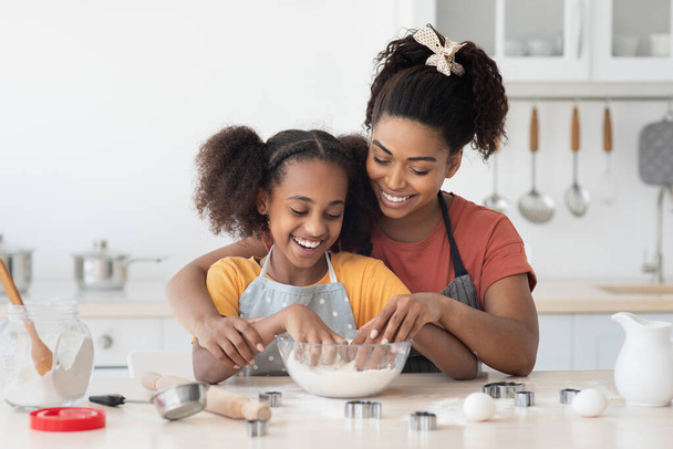 Madre negra mostrando a su hija adolescente cómo hornear galletas - Foto, Imagen