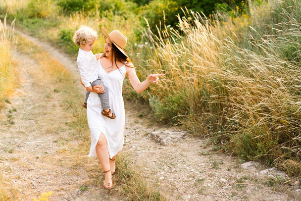 Moeder toont mooie plaatsen aan haar zoontje tijdens het wandelen in de natuur - Foto, afbeelding