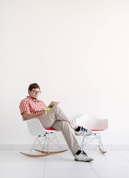 Online vásárlási koncepció. Fiatal férfi ül a széken, és online vásárlás táblagéppel nézi a hitelkártyát, másolja a helyet - Fotó, kép
