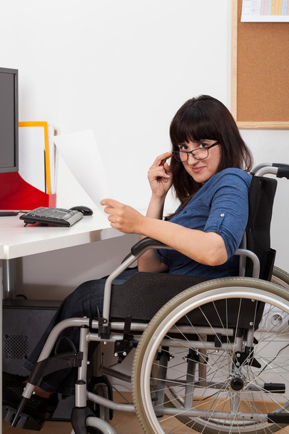 Disabled young girl on wheelchair working in her office - Фото, изображение