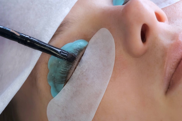 Cosmetologo mette vernice nera sulle ciglia delle donne procedura laminazione ciglia. - Foto, immagini