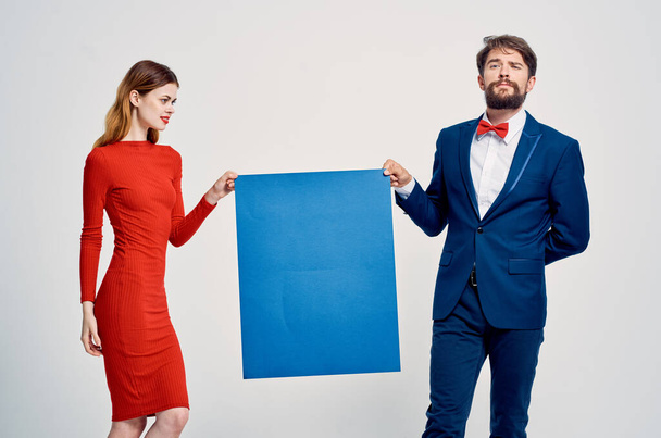 スーツ姿の男が赤いドレス姿の女性の隣に青いモップのポスター - 写真・画像