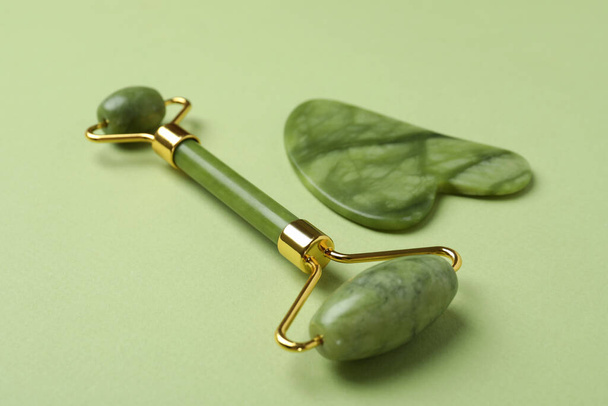 Face roller and gua sha on green background - Photo, Image