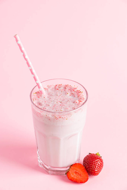 Verse milkshake met aardbeien op een roze achtergrond. Zomer drankje met bessen in een glas. Plaats voor tekst. - Foto, afbeelding