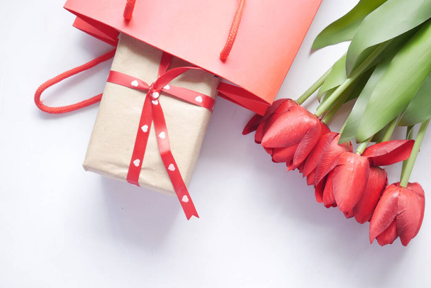 gift box in a shopping bag and red tulip flower on table  - Zdjęcie, obraz