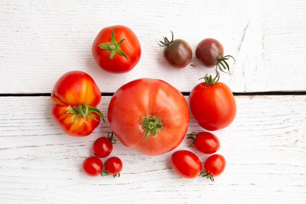 Above view or group of different shape, size and color tomatoes in row, copy space on white brown background. - Photo, Image