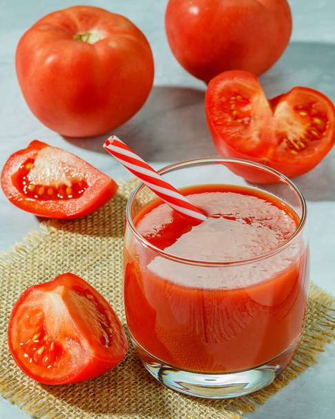 El jugo de tomate y los tomates en rodajas en una mesa - Foto, Imagen