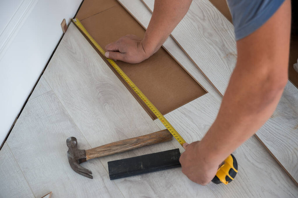 Close-up de mãos de homem com roler instalar piso laminado na nova sala. Trabalhador cobrindo inundações em casa. renovação. Faça-você-mesmo - Foto, Imagem