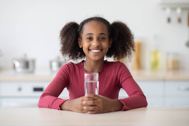 Χαρούμενη Αφροαμερικανή έφηβη που πίνει νερό. - Φωτογραφία, εικόνα