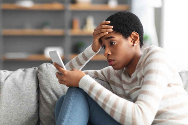 自宅でスマートフォンで悪いメッセージを読んだ後に若い黒人女性の動揺 - 写真・画像