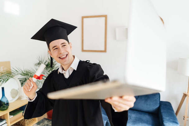 Kaukasische jongeman voelt zich erg opgewonden om zijn bachelors diploma te ontvangen - Foto, afbeelding