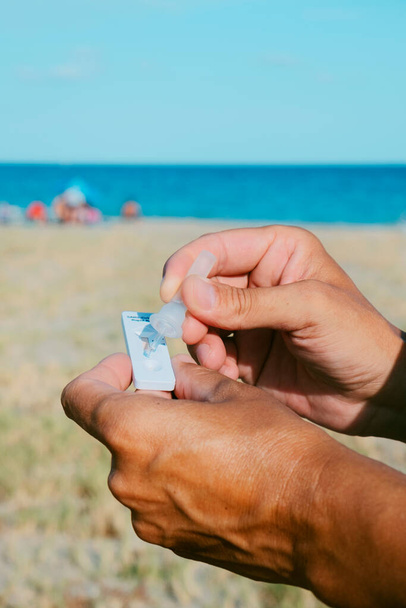 крупним планом молодий кавказький чоловік на пляжі розмістив свій власний зразок у пристрій для діагностики ковадла-19
 - Фото, зображення