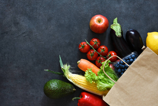 Paper bag with food. Vegetables in a bag from a supermarket. Advertising on the board. Food delivery. - Foto, imagen
