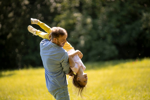 Father with cute little daughter having fun on the grass at the park - Foto, Imagen