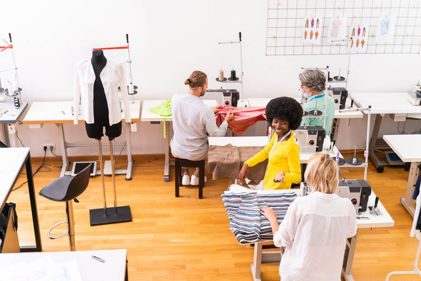 Multiethnic team of fashion designers working in a clothing start-up workshop - Multiracial group of stylists, tailor designers and dressmakers working on a new collection - Photo, image
