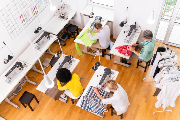 Multiethnic team of fashion designers working in a clothing start-up workshop - Multiracial group of stylists, tailor designers and dressmakers working on a new collection - Foto, immagini