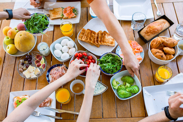 Food on the table. Breakfast on the terrace with the family. Friends are eating at the table. World Food Day Healthy Food Table Top View Party Birthday Lots of food for breakfast. Buffet. Avocado, salmon, cheese, cherry. Family eats - 写真・画像