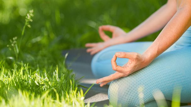Mujer joven entrenadora en chándal azul medita en pose de yoga loto cogido de la mano sobre rodillas en leggins - Foto, Imagen
